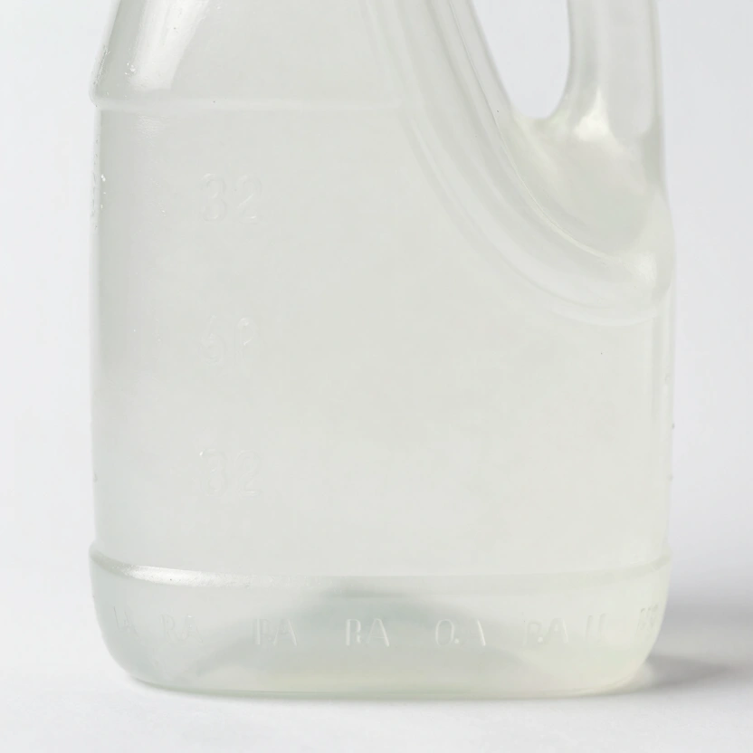 Close-up of a motor oil bottle production date stamp and expiration marking on the bottom of a plastic container, crisp detail, neutral white background, studio product lighting, no other text visible, no watermarks